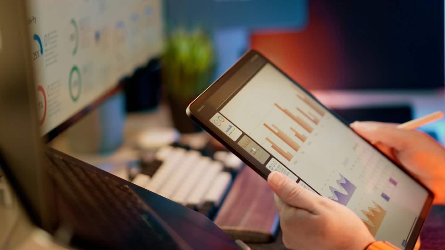 Person analyzing business charts on a tablet at a desk.